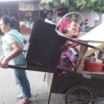 Madre trabajadora cuida de su hija en una parada de buses en Managua nicaragua