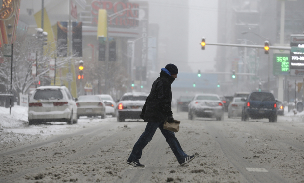 A man crosses a snowy street in downtown Chicago on Sunday, Jan.