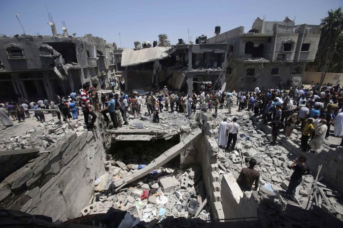 En la imagen, palestinos se reúnen cerca a casas destruidas, que según testigos fueron dañadas por un ataque aéreo israelí, en Khan Younis, en el sur de la Franja de Gaza.