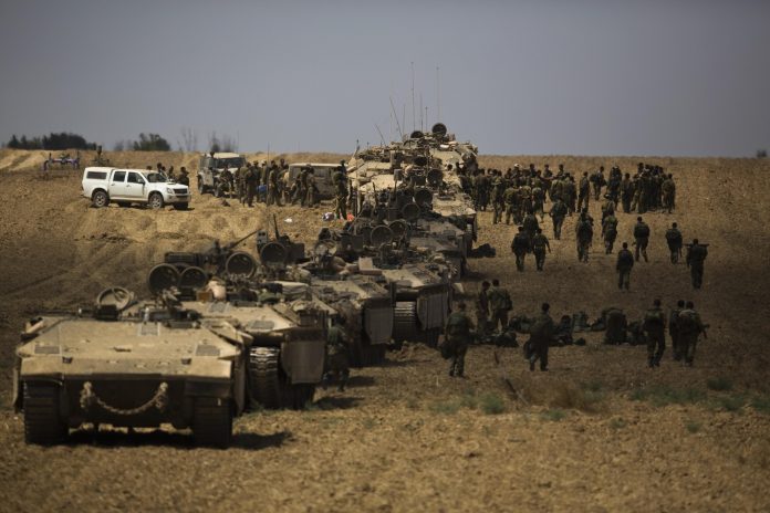 En la imagen, soldados israelíes caminan junto a sus tanques tras regresar a Israel desde la Franja de Gaza.