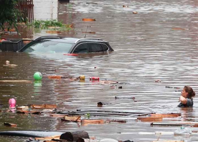 Una mujer trata de cruzar la calle con el agua al cuello en Lieja, Bélgica