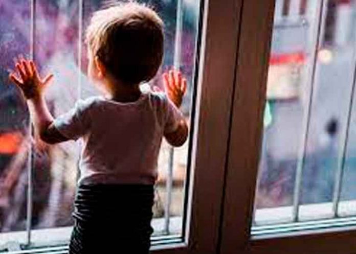 Menor de edad frente a una ventana