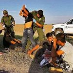 Agente policial de la frontera revisando a un grupo de migrantes