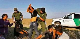 Agente policial de la frontera revisando a un grupo de migrantes