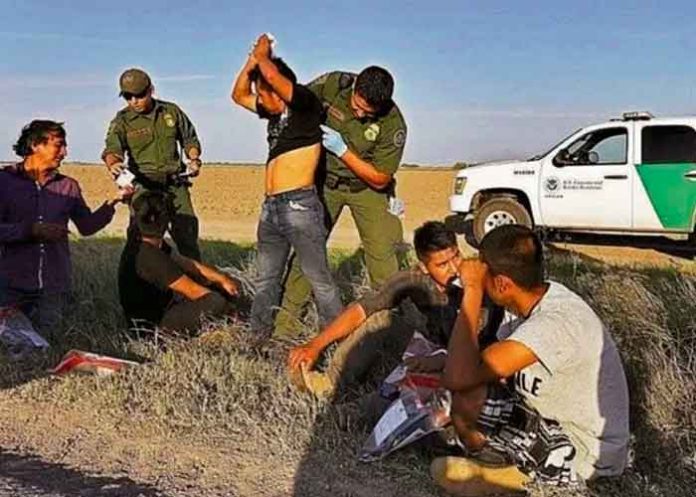 Agente policial de la frontera revisando a un grupo de migrantes
