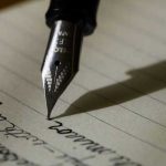 Pluma escribiendo sobre una hoja de papel