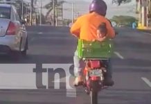 Momento en que un motorizado lleva a una niña en una cajilla, a bordo de una moto, en Managua
