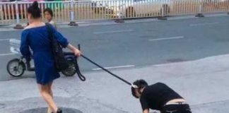Mujer paseando a un hombre como si fuera un perro